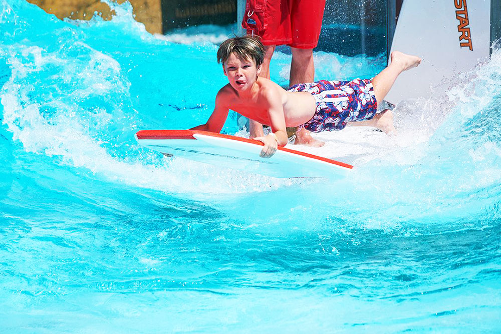 Boy on water board riding wave at cowabunga beach, Water World