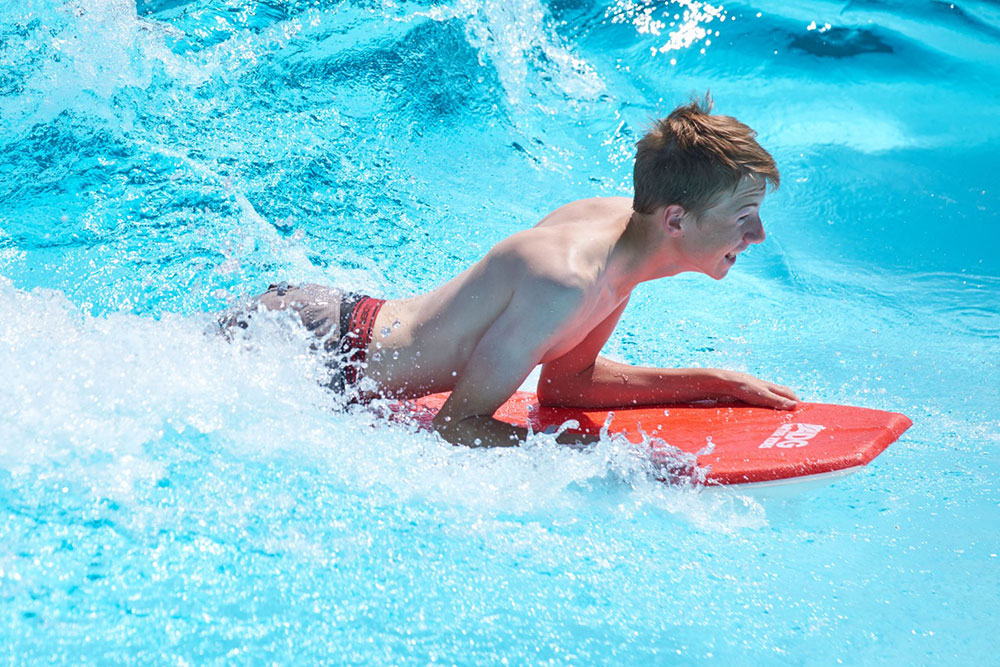Boy on water board riding wave at cowabunga beach, Water World