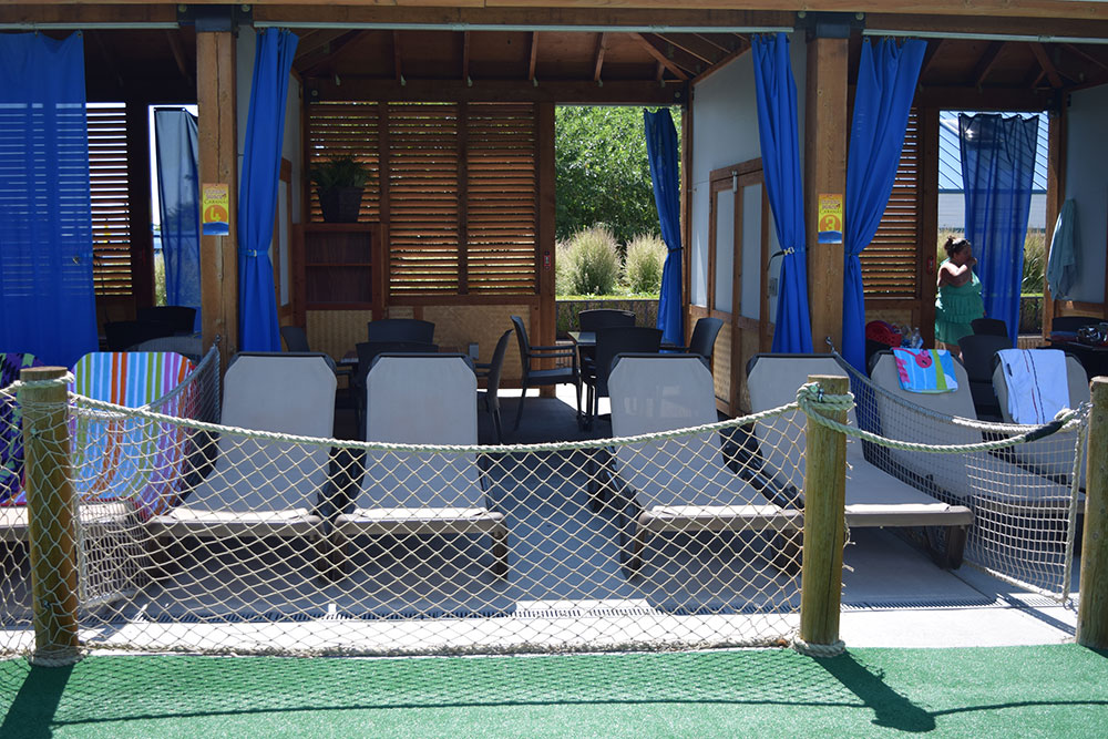 Outside view of a cabana at sunset beach with tables, chairs and sun chairs