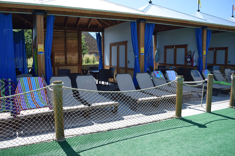 Outside view of a cabana at sunset beach with tables, chairs and sun chairs