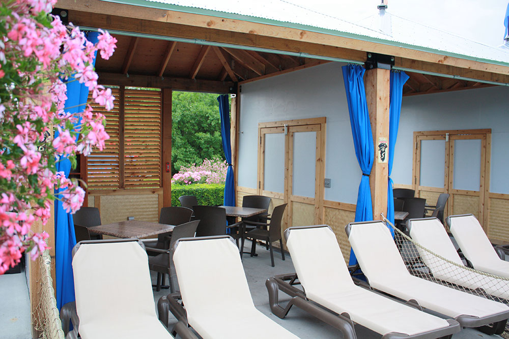 Outside view of a cabana at sunset beach with tables, chairs and sun chairs